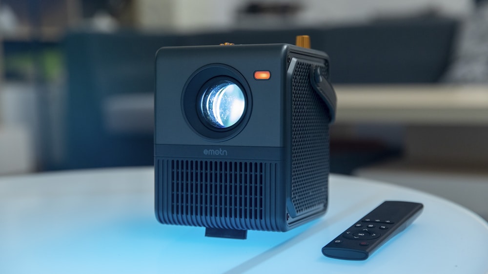 a small projector sitting on top of a table next to a remote