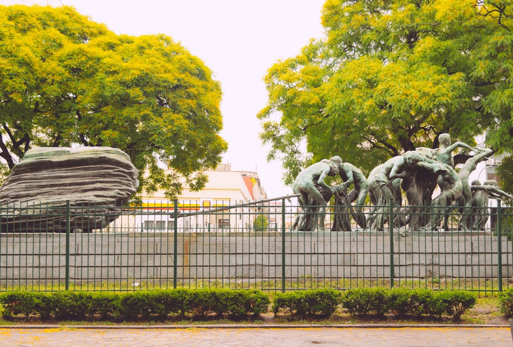 a statue of a group of people behind a fence