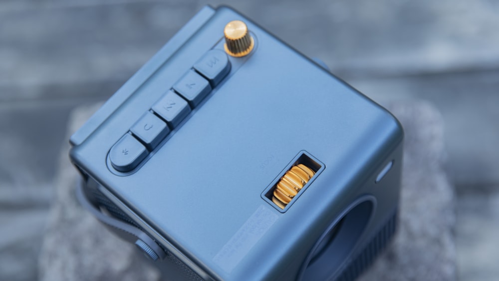 a small blue device with a gold button on it