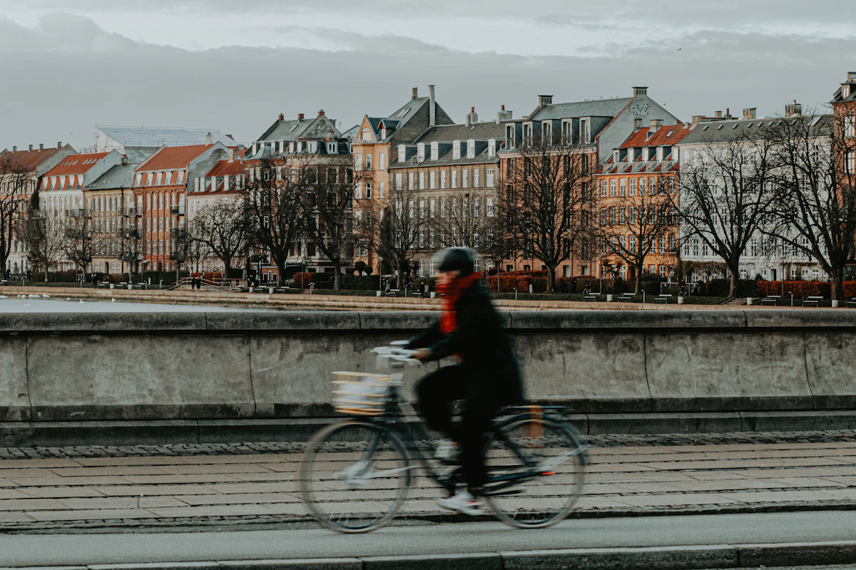 Copenhaga - biciclist pe pod, cu fațadele clasice ale orașului în spate