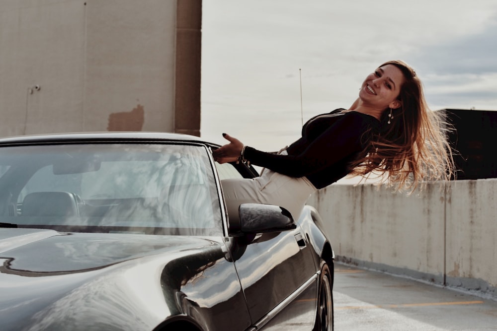 a woman leaning on the hood of a car