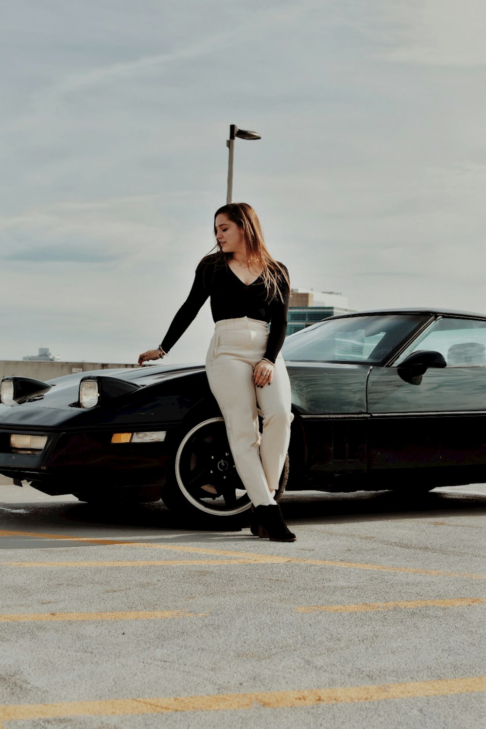 a woman standing next to a car in a parking lot