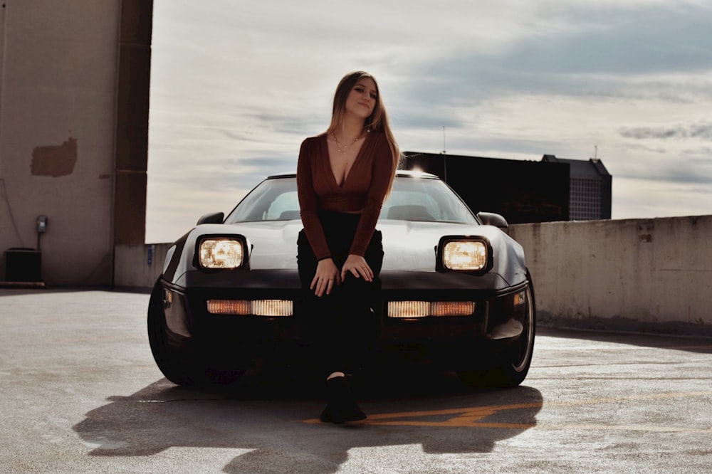 a woman sitting on the hood of a car