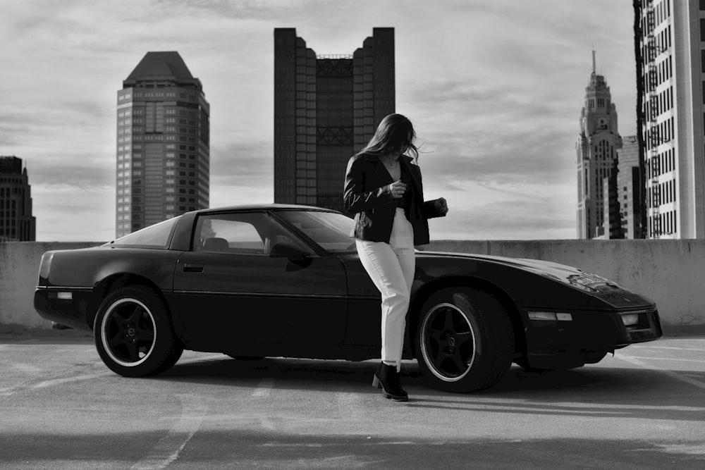 a woman standing next to a car in a parking lot