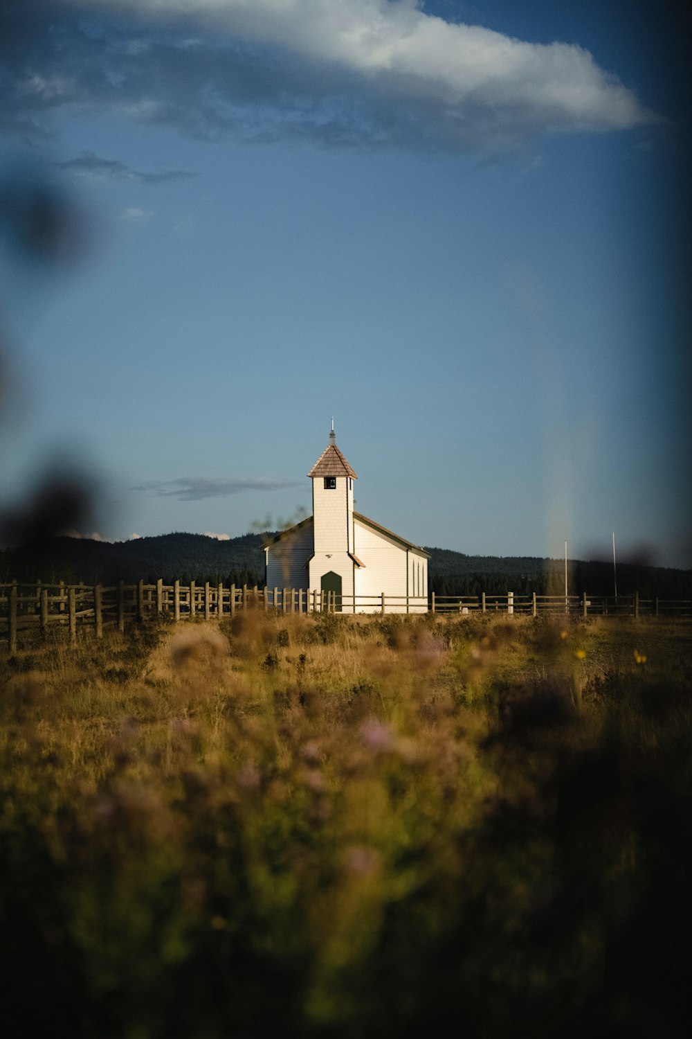 a white church with a steeple in a field