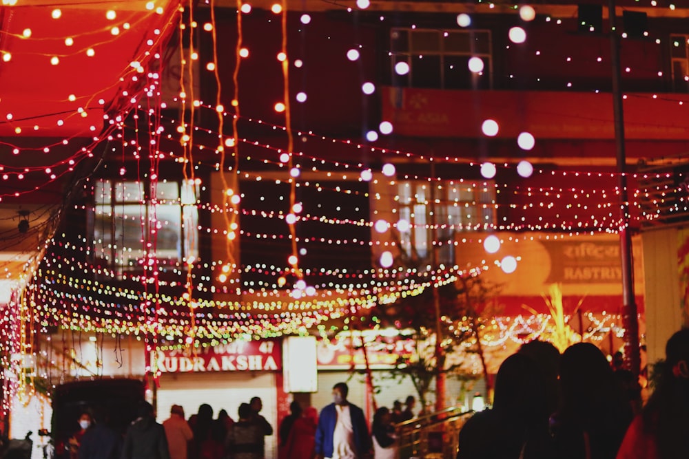 a group of people walking down a street covered in lights