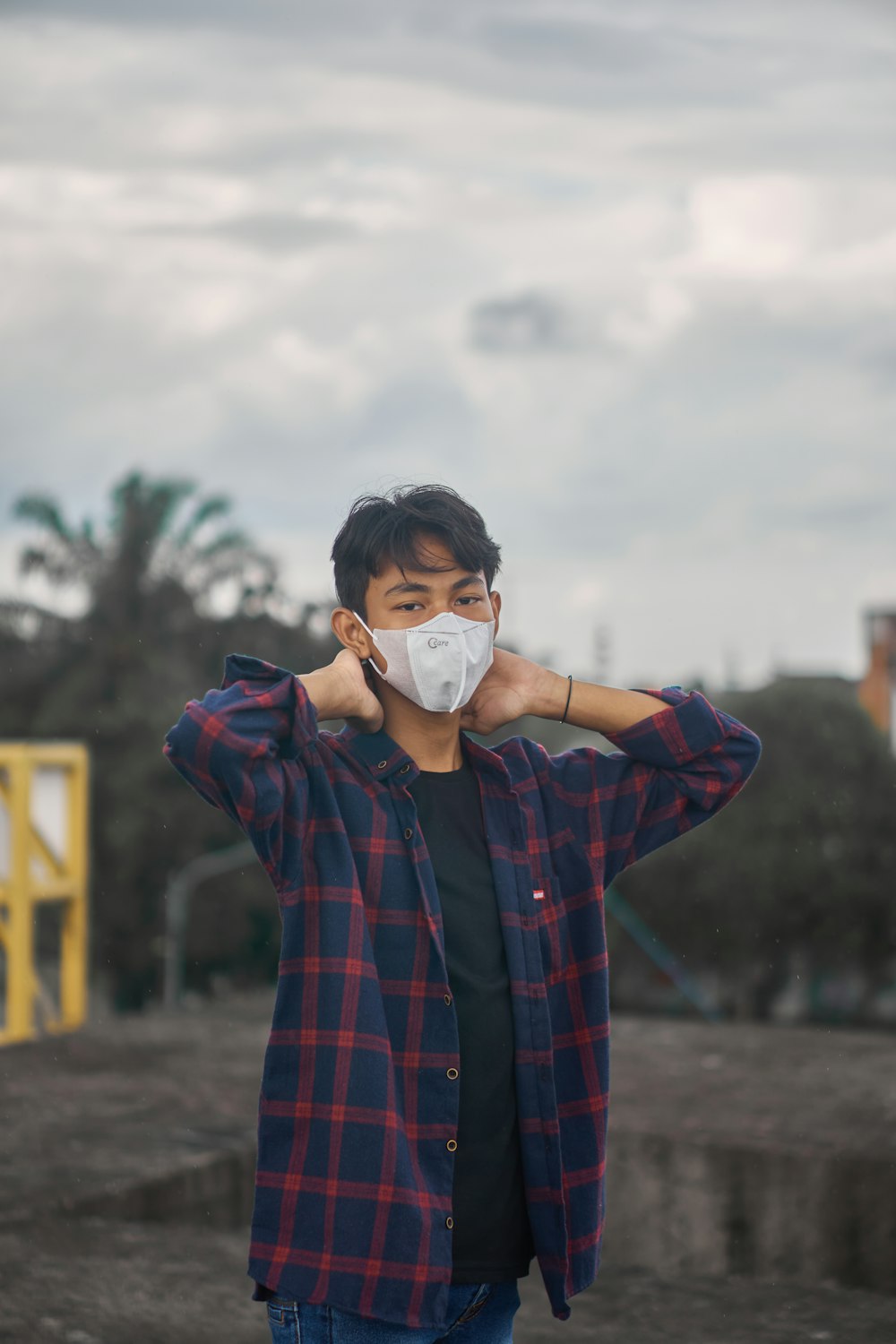 a man wearing a face mask while holding his hands to his ears