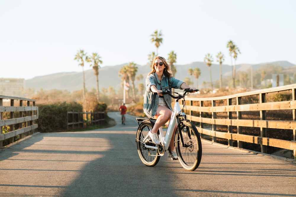 a woman riding a bike across a bridge