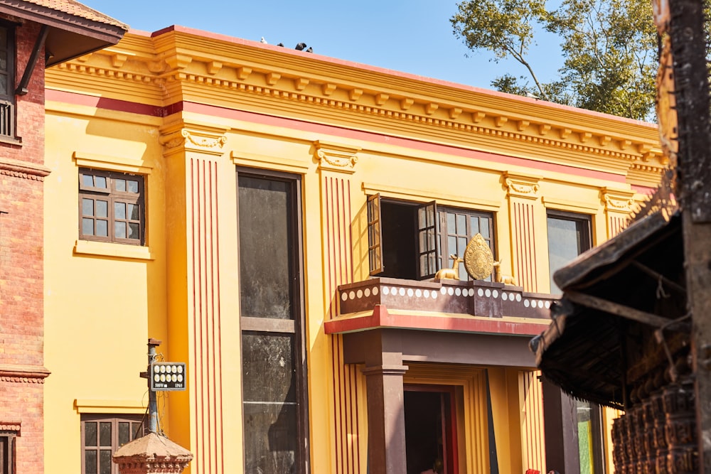 a yellow building with a cat sitting in the window