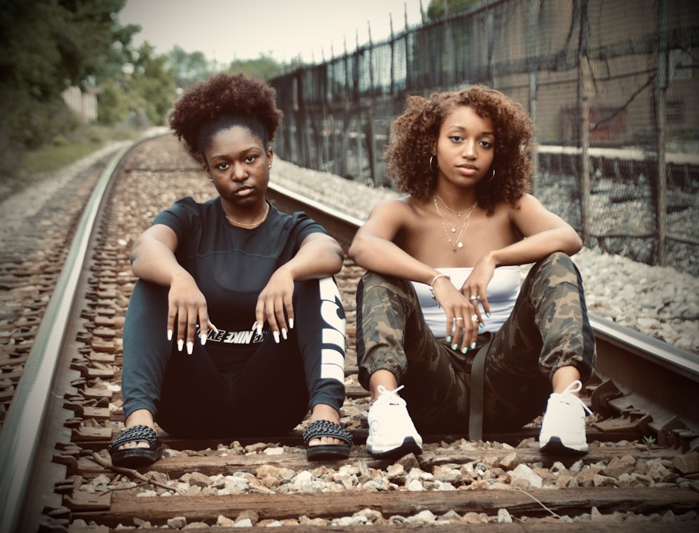 a couple of women sitting on top of train tracks