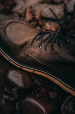 A rugged pair of high-top shoes set against a backdrop of an outdoor adventure scene.