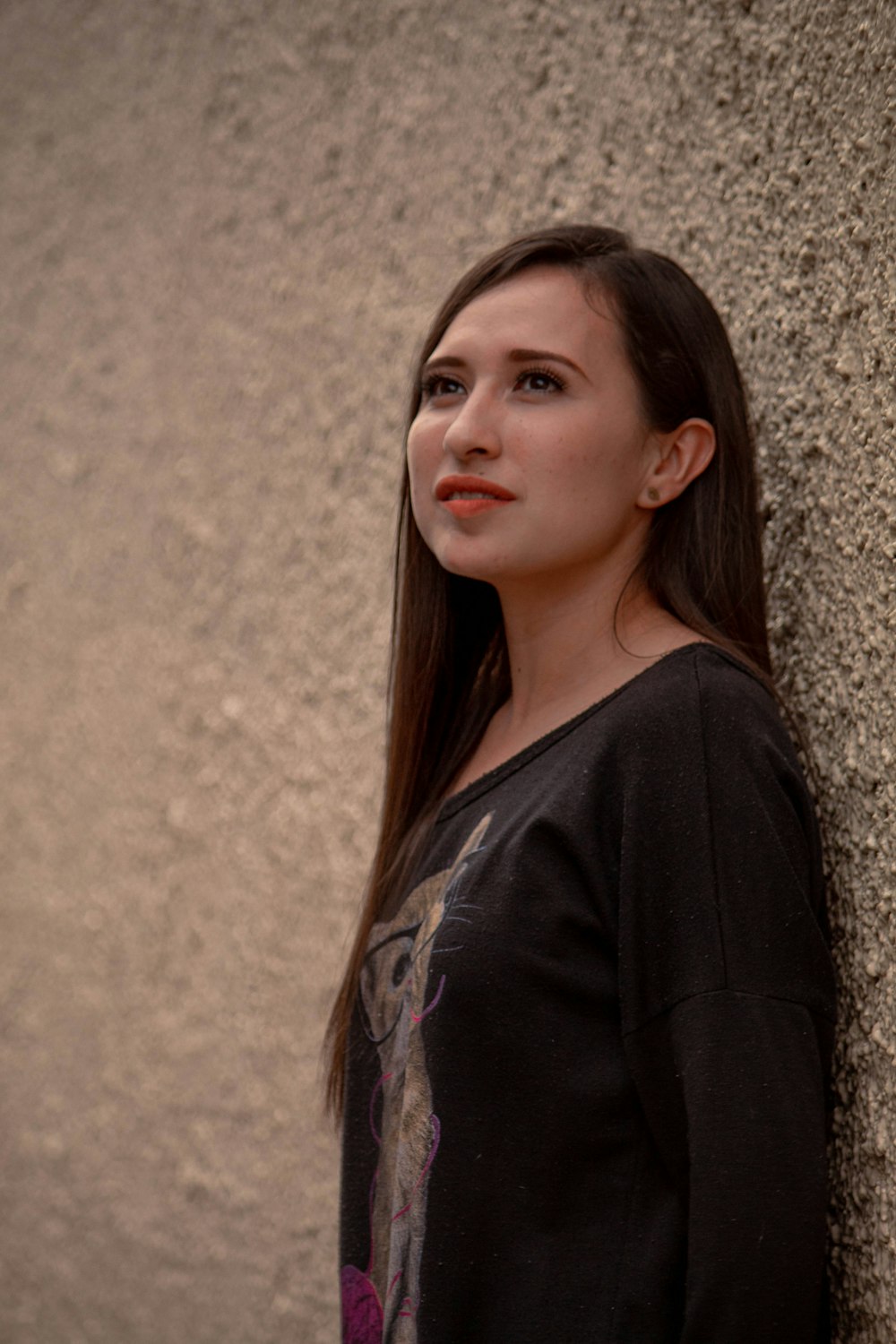 a woman leaning against a wall with a cell phone in her hand