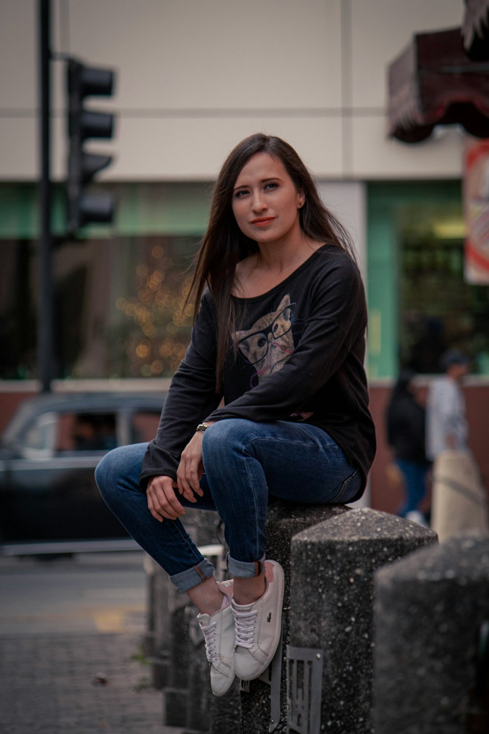 a woman sitting on top of a cement pillar