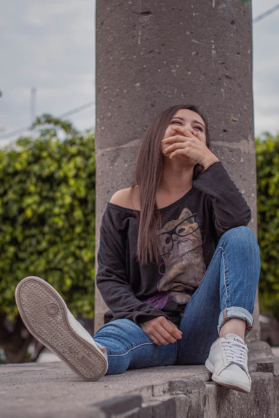 a woman sitting on a ledge with her hand on her face
