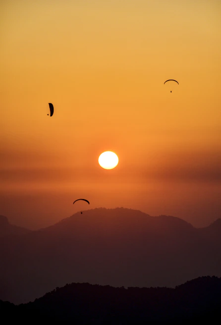 Sunset over a mountain peak with adventurers relaxing and admiring the view