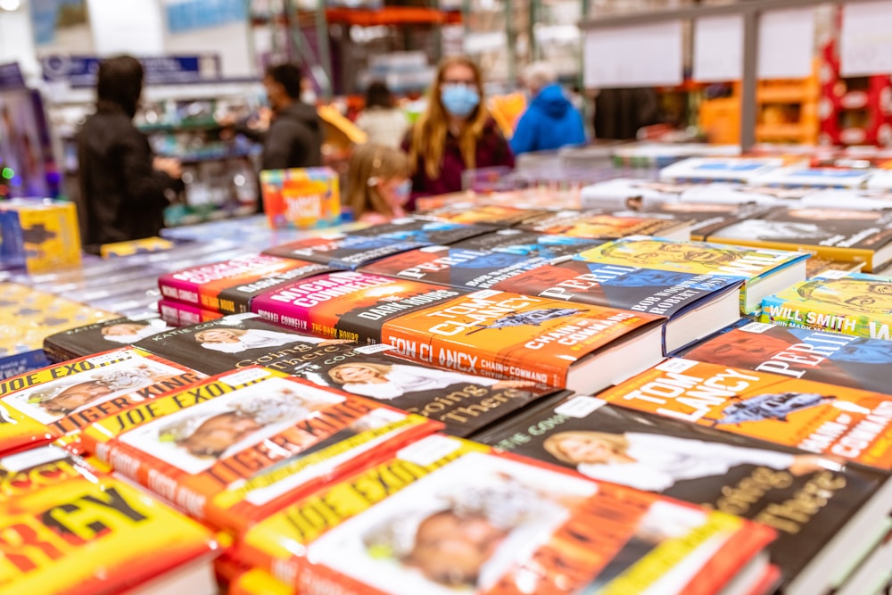 uma mesa cheia de livros infantis com pessoas ao fundo