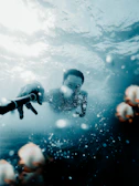 Close-up of an underwater case protecting a camera beneath crystal-clear ocean waves.