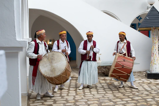 A vibrant group of local musicians playing traditional instruments in a sunlit courtyard of an ancient Kashi haveli.