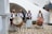Four men in traditional attire are playing musical instruments. Two of them are holding large drums, one is playing a flute-like instrument, and the other is holding another drum. They are standing on a stone courtyard surrounded by white walls and arches.