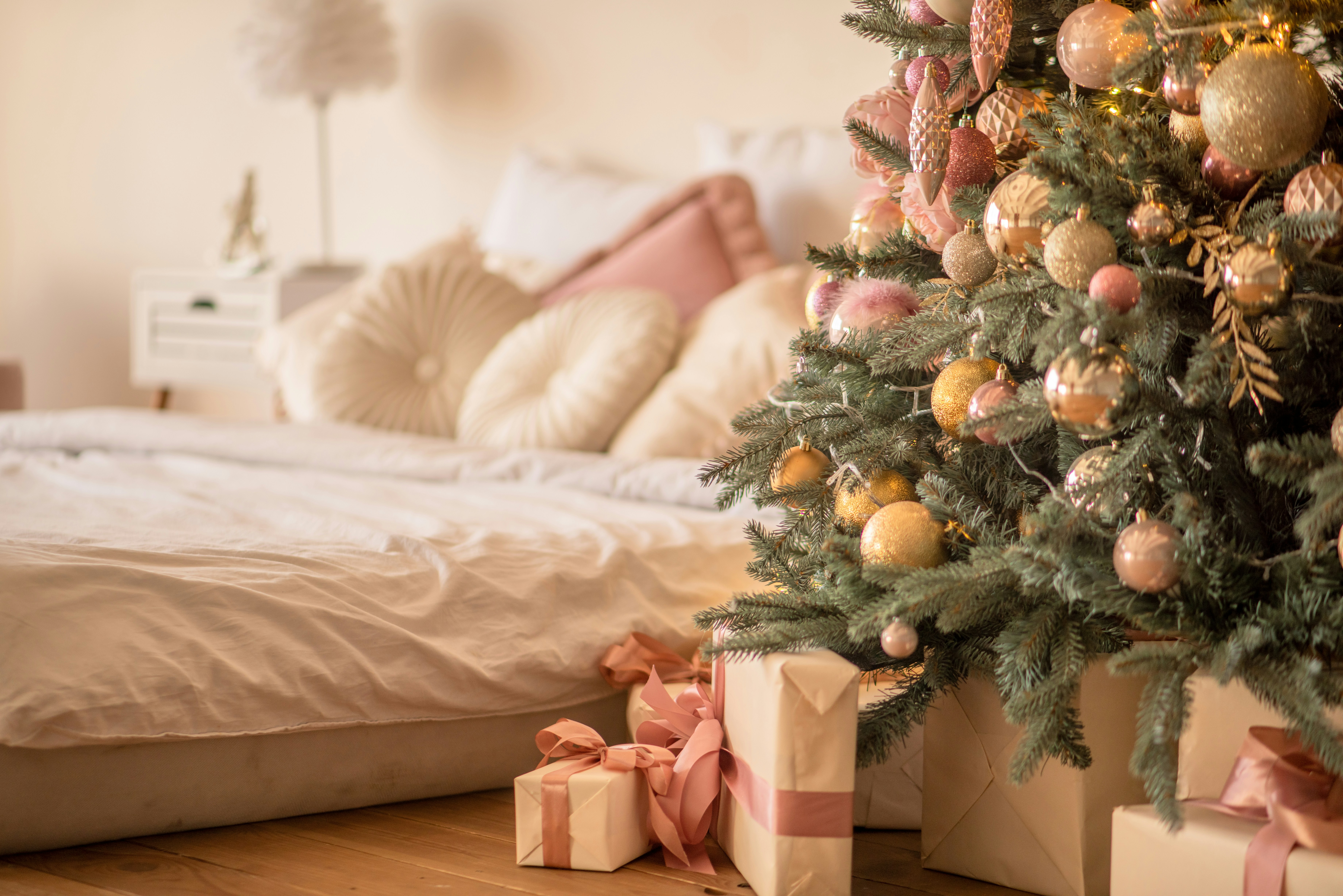 a decorated christmas tree in a bedroom next to a bed