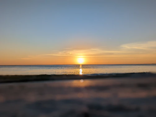 A serene sunset over a calm ocean with soft pastel colors reflecting on the water.