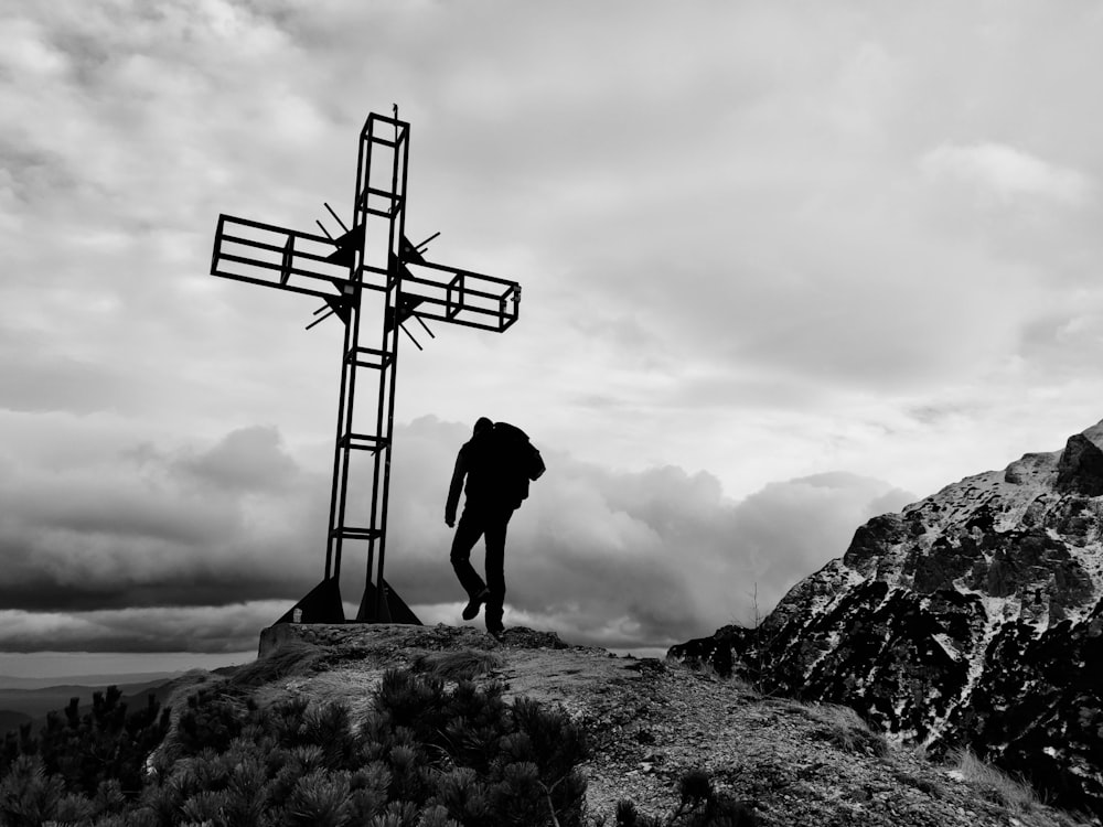 a man standing on top of a mountain next to a cross