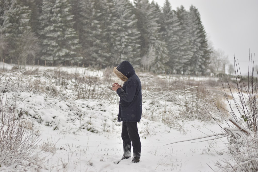 eine Person, die im Schnee vor einigen Bäumen steht