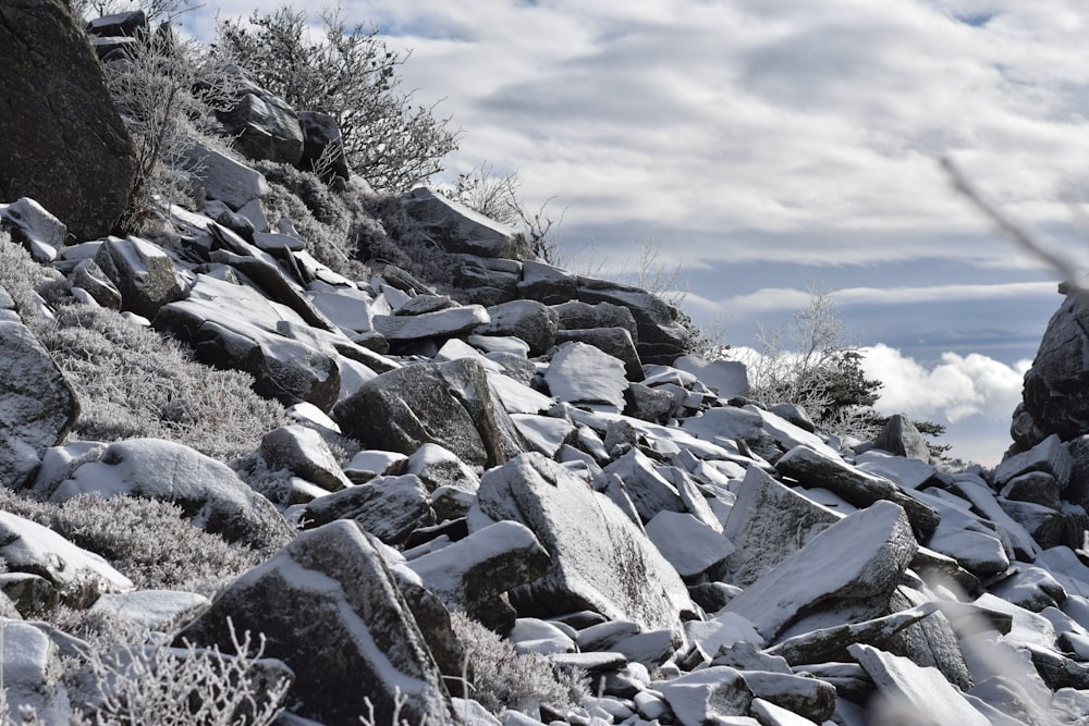 a rocky hillside covered in snow under a cloudy sky