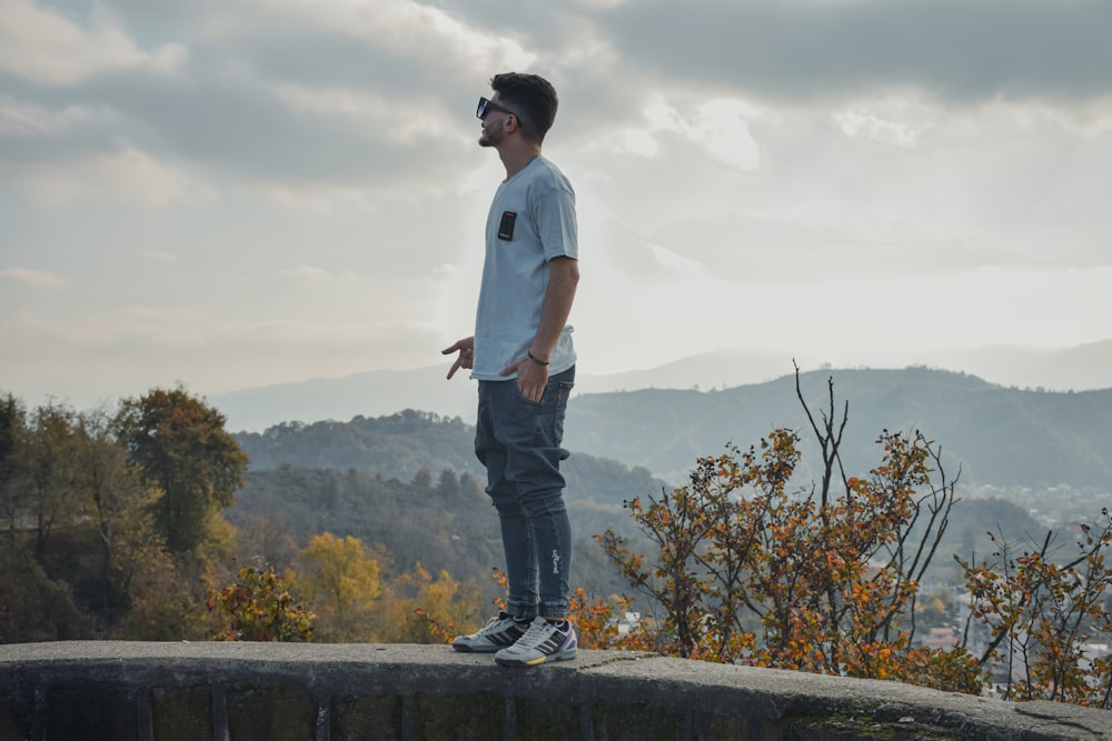 a man standing on top of a rock next to a forest