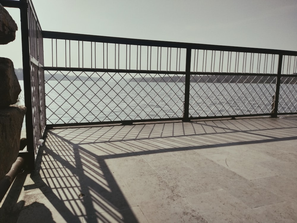 a metal fence next to a large body of water