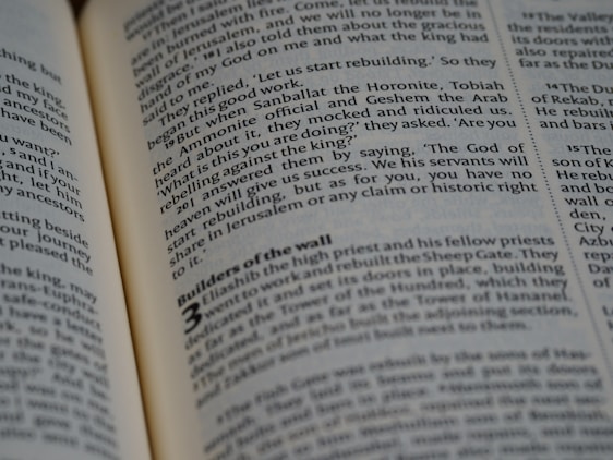 An open book with text in English is visible, showing various paragraphs and sections. The focus is on the middle of a page, where part of the text appears bolder, possibly indicating a heading or subheading. The page is slightly curved, suggesting the book is partly closed.
