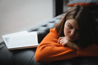 a woman laying on a couch with a book