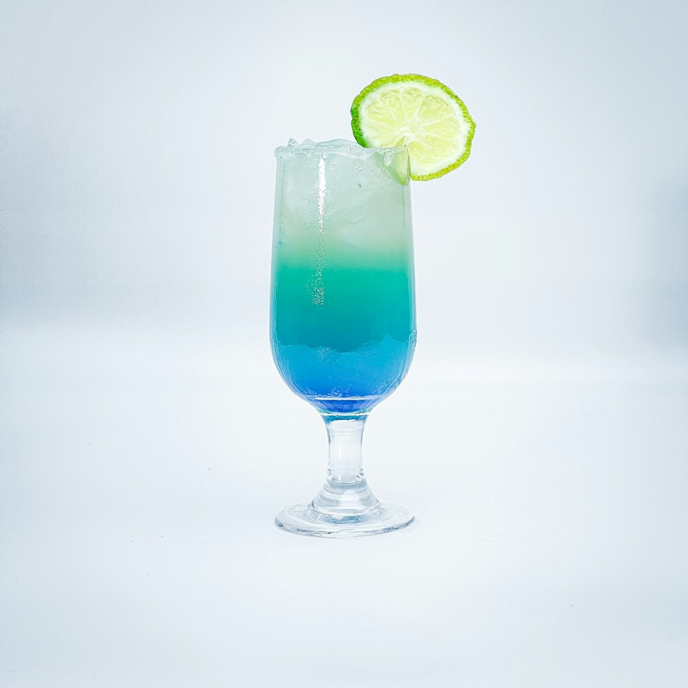 a blue and green drink with a lime slice on top