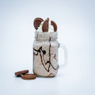 a glass jar filled with cookies and whipped cream