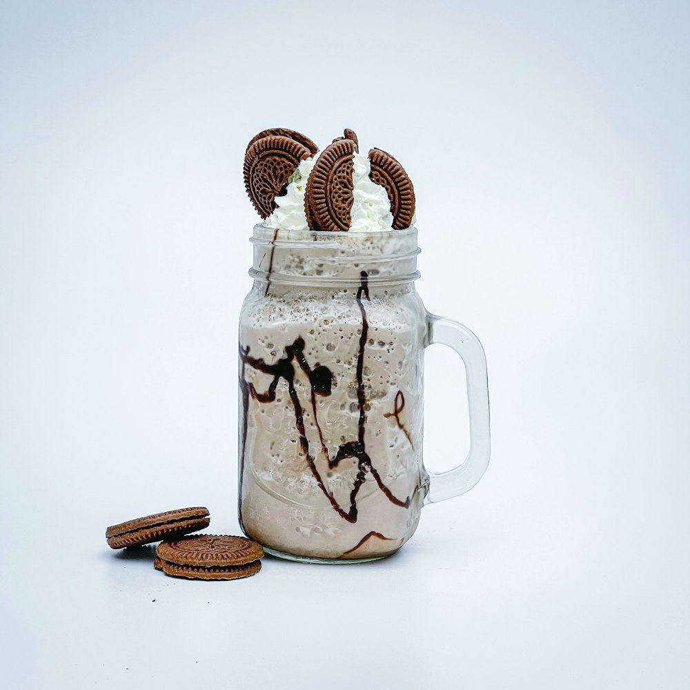 a glass jar filled with cookies and whipped cream