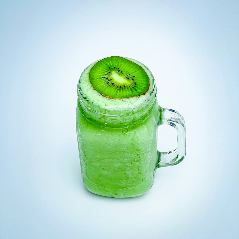 a green drink with a kiwi slice on top of it