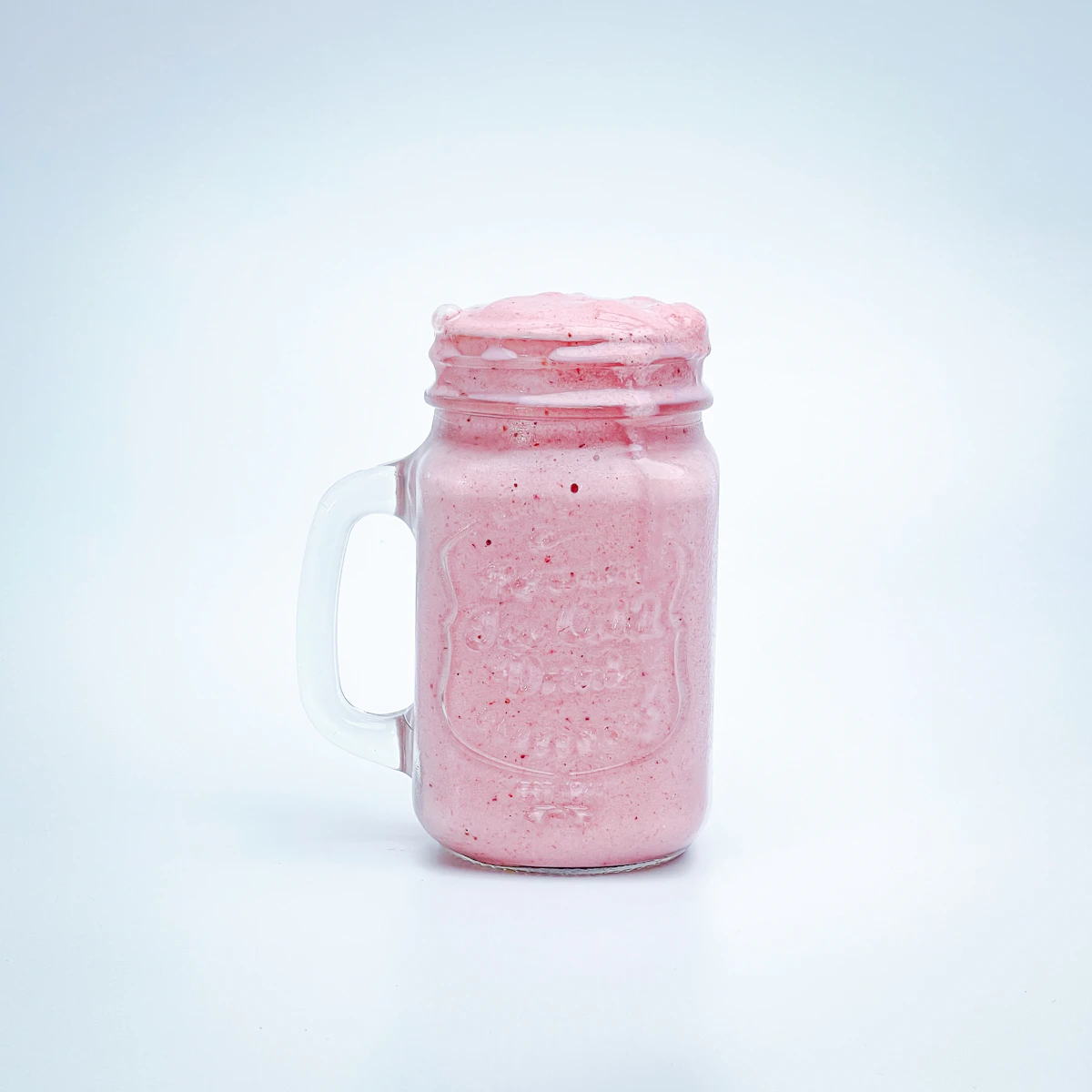 A pink milk drink in a mason jar