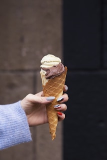 a woman holding a chocolate and vanilla ice cream cone