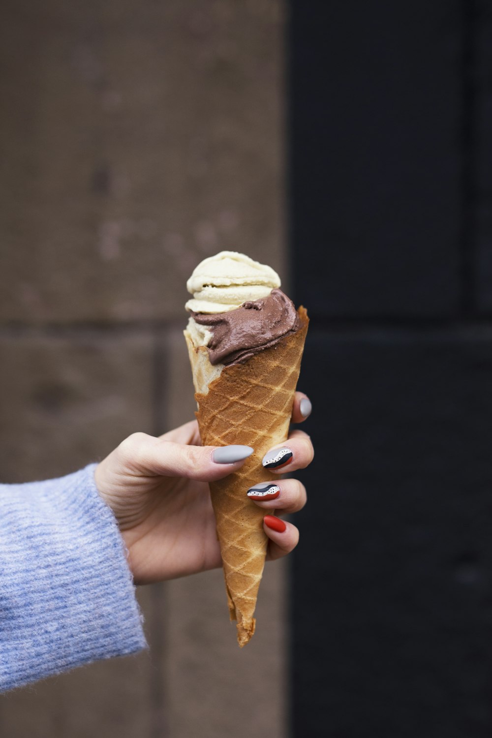 a woman holding a chocolate and vanilla ice cream cone