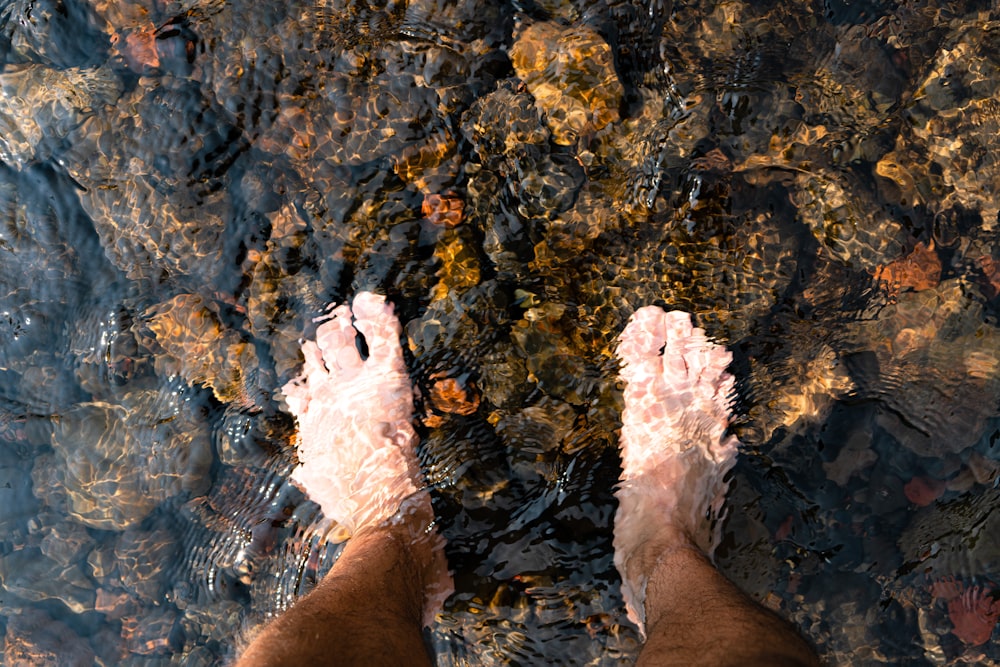 eine Person, die im flachen Wasser steht und die Füße im Wasser hat