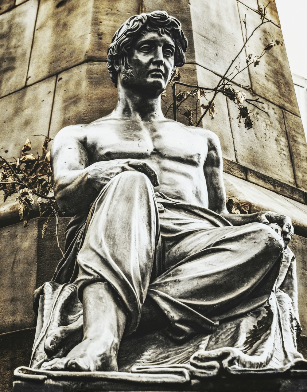 a statue of a man sitting in front of a tall building