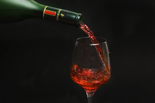 Close-up of a rich red wine being poured into a crystal glass at the bar.