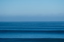 a large body of water sitting under a blue sky