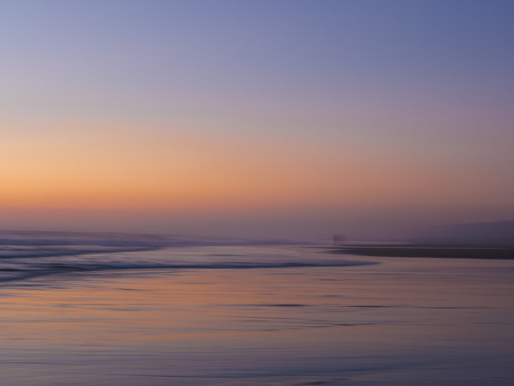 a person walking on the beach at sunset