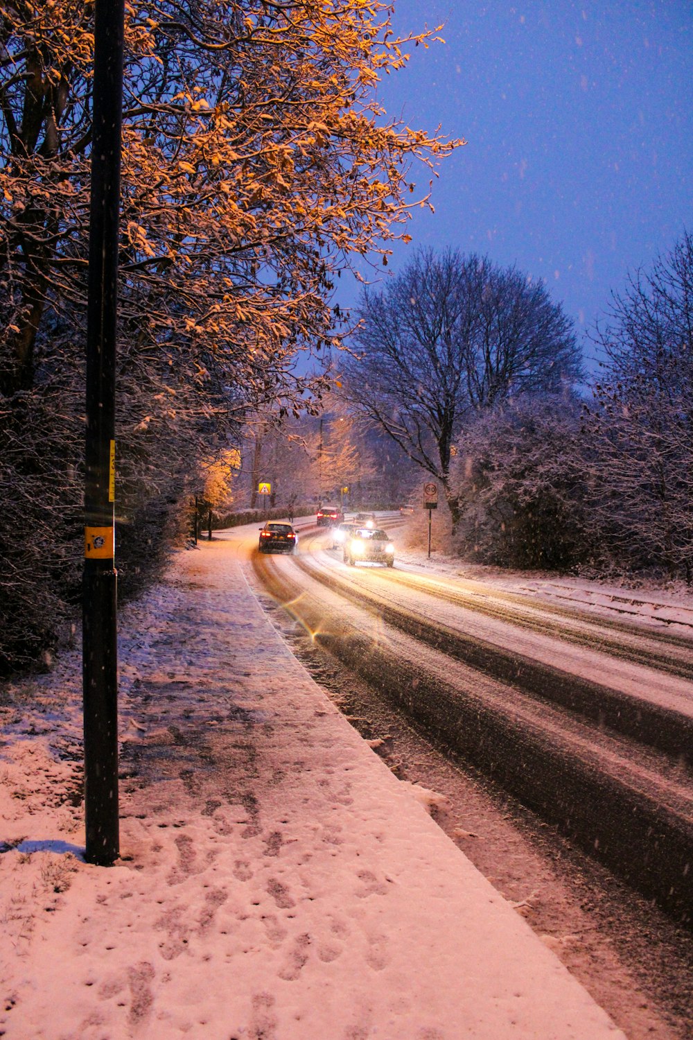 a snowy street with cars driving down it