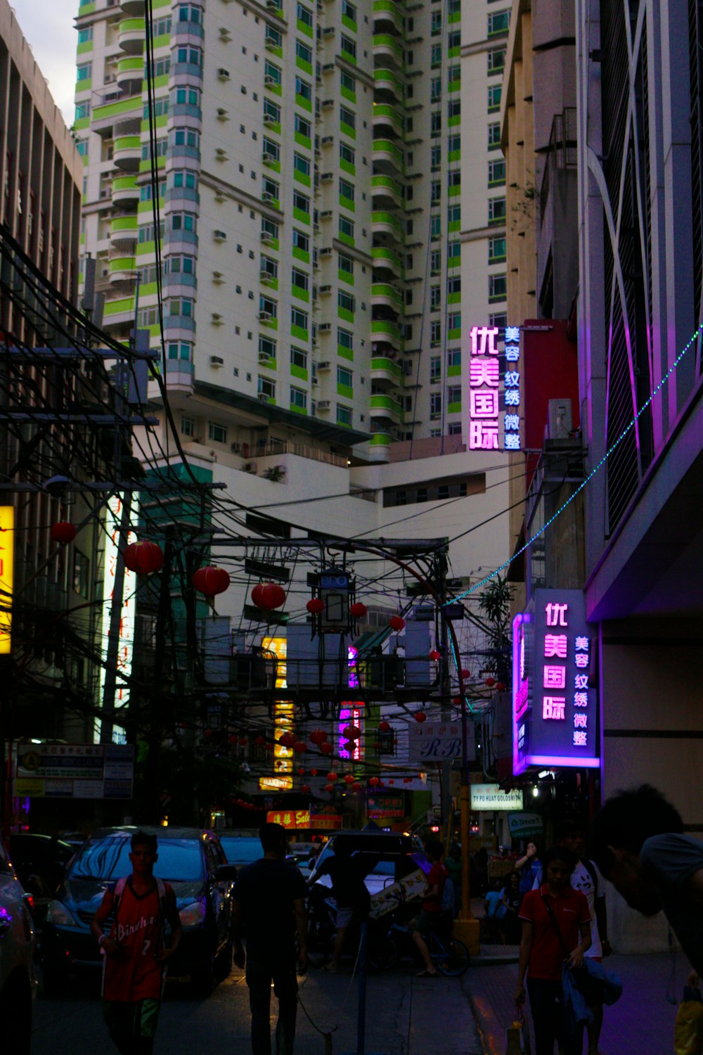 a group of people walking down a street next to tall buildings