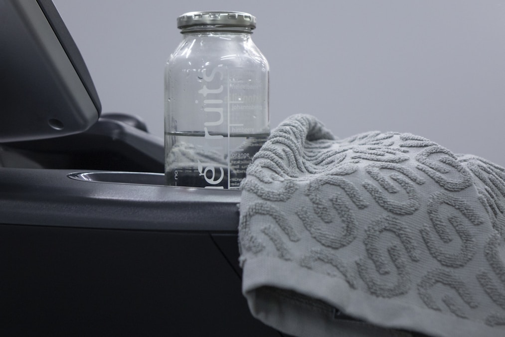 Water bottle and folded gray towel resting on a cardio machine console