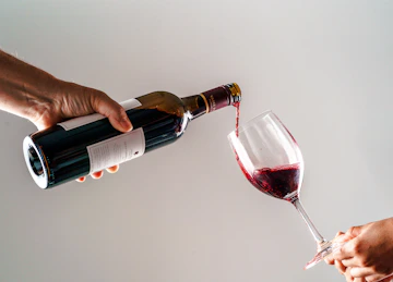 a person pouring a glass of wine into another person's hand