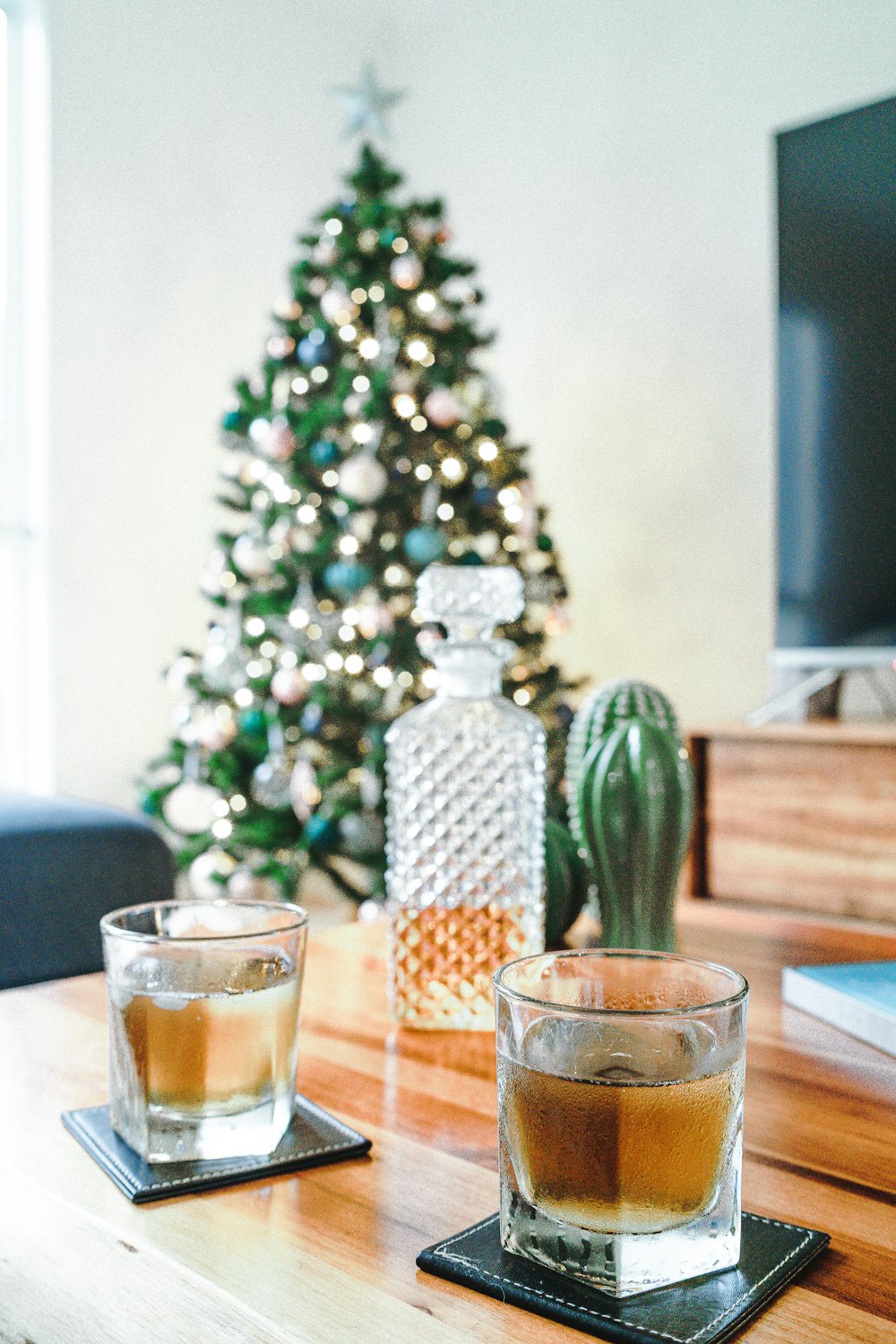 two glasses of liquid sitting on a table in front of a christmas tree