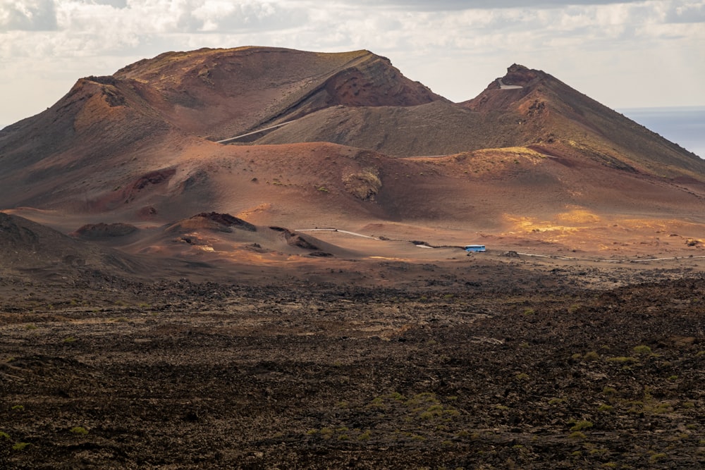 a group of mountains in the desert under a cloudy sky